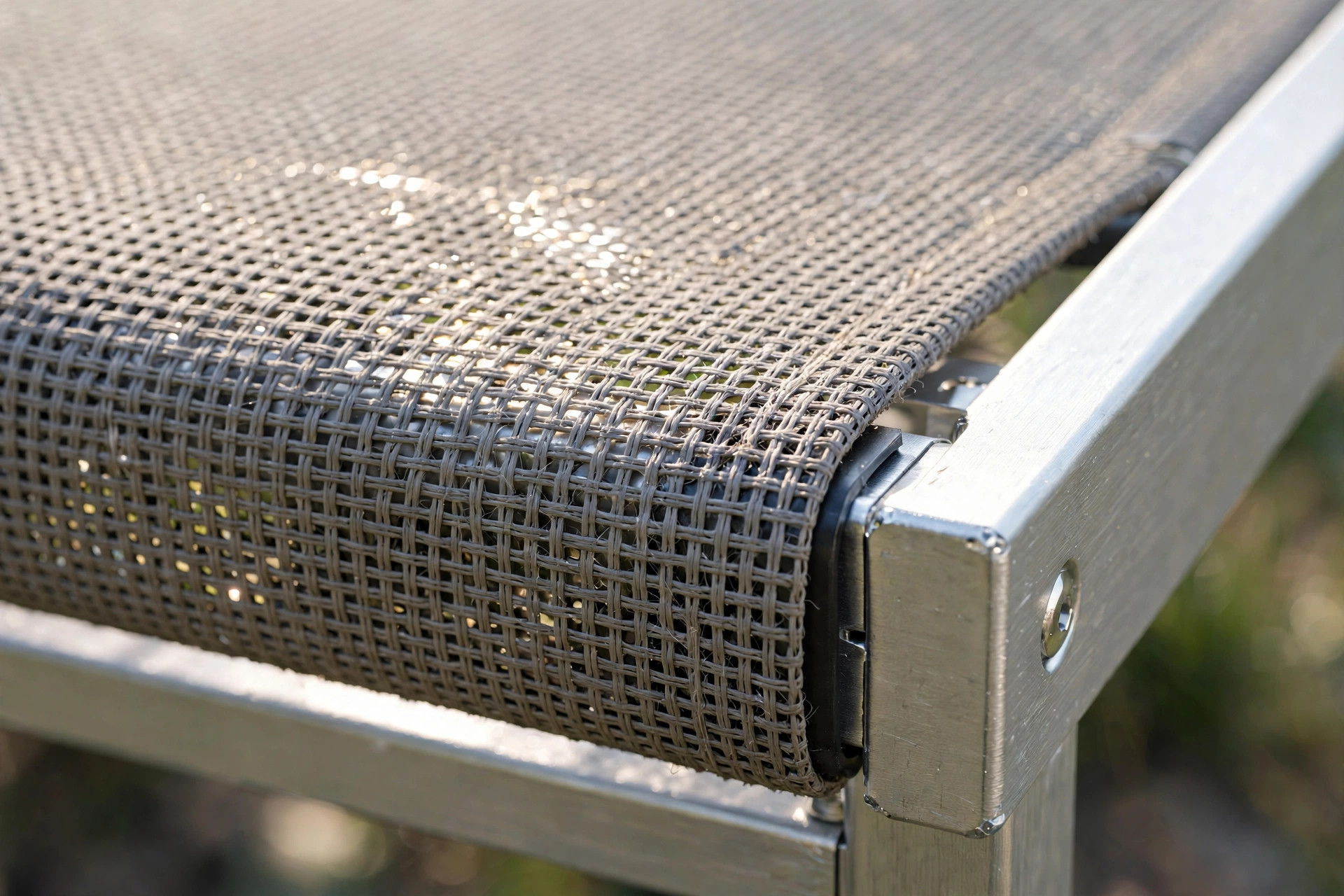 Close-up of breathable woven mesh fabric stretched taut over the corner of an aluminium elevated dog bed frame.